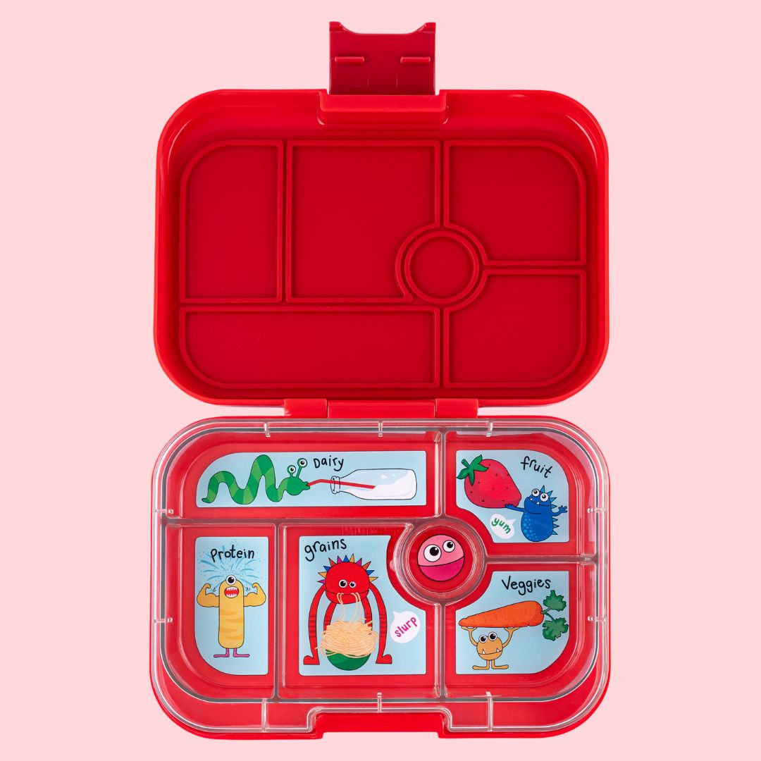 Red lunch box with compartments and cartoon illustrations on a pink background