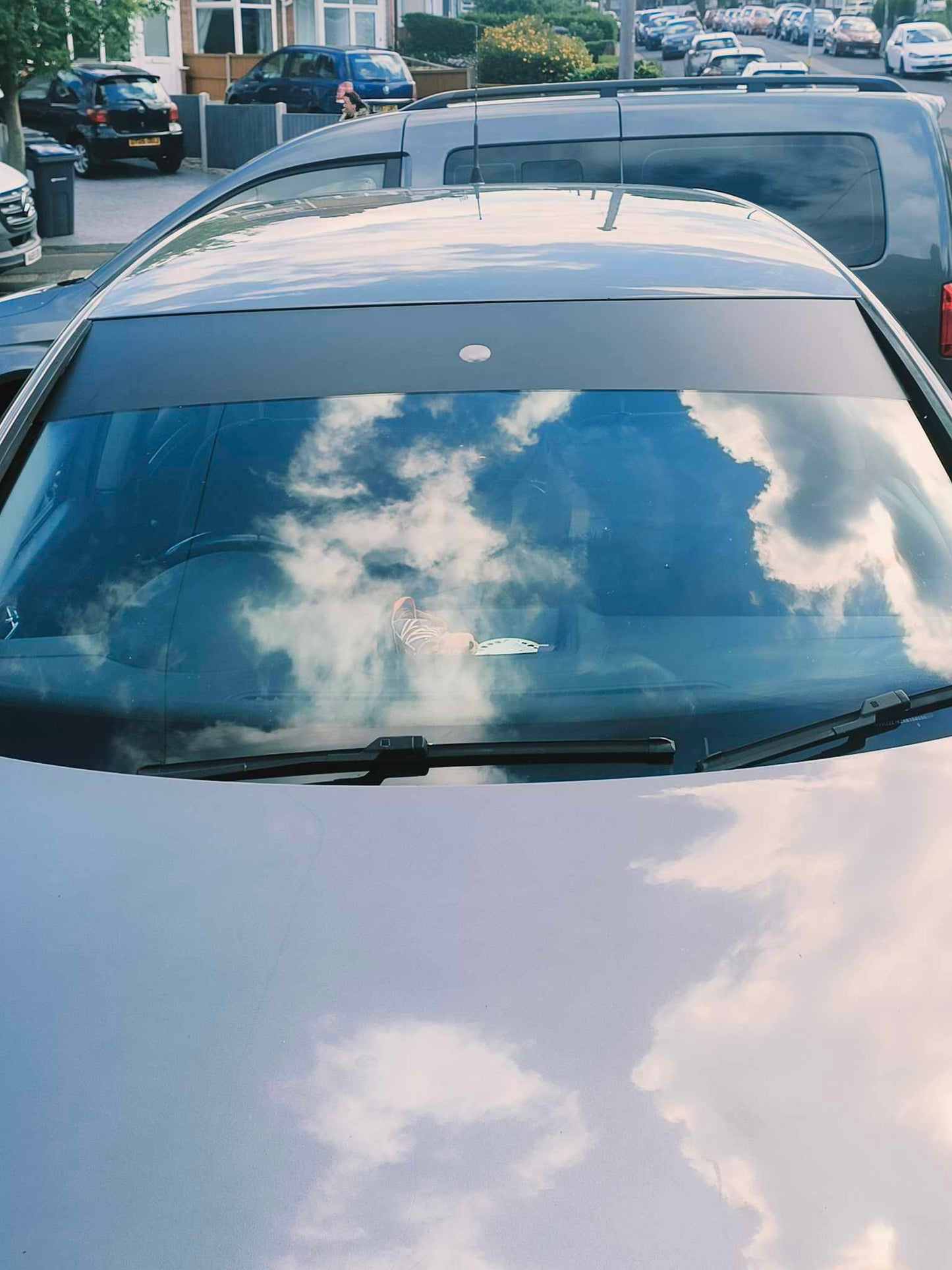Car windshield with cloud reflections in a parking lot