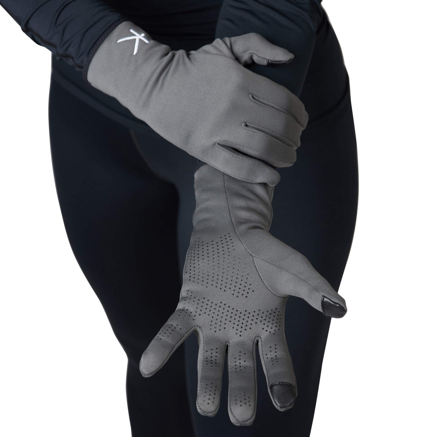 Gray gloves worn by a person against a black background
