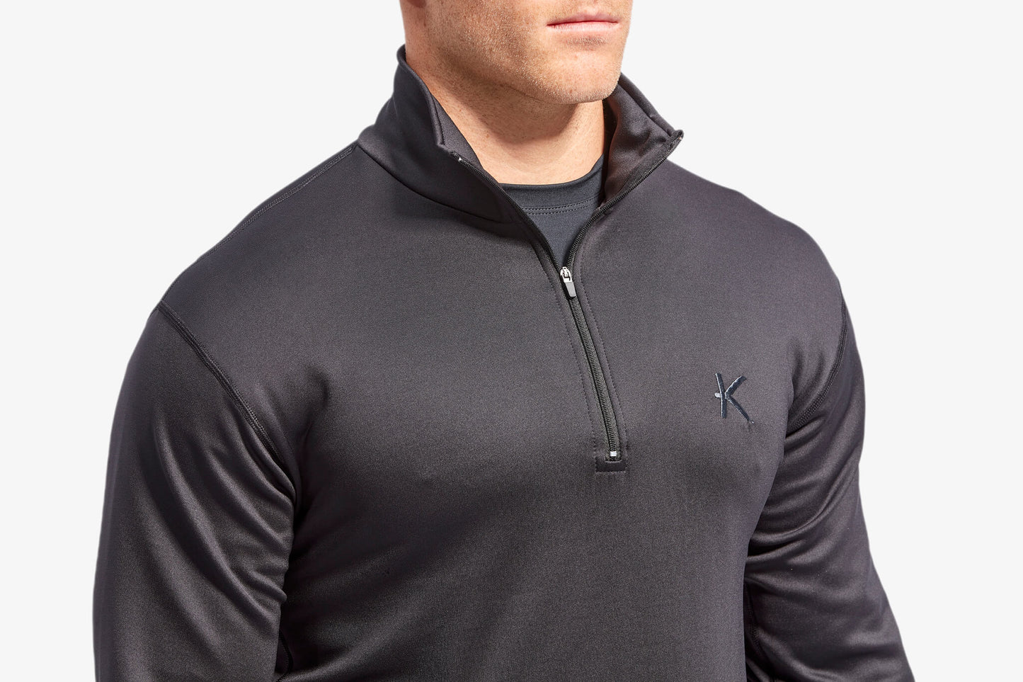 Man wearing a dark gray quarter-zip pullover with a brand logo on a light gray background