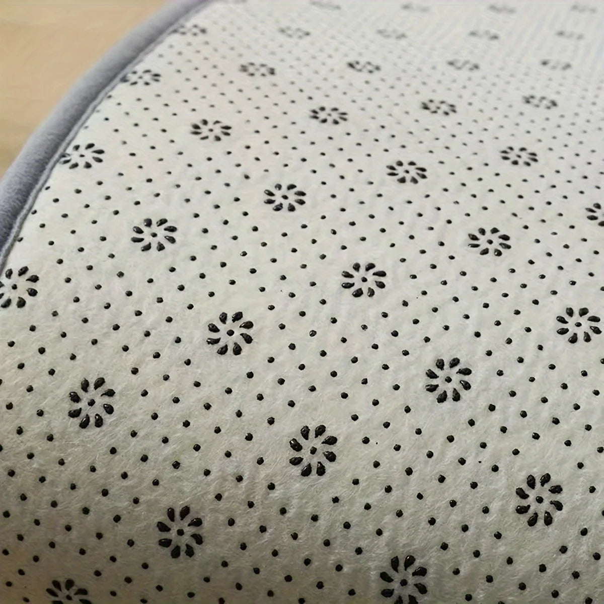 Close-up of a textured fabric with black floral patterns on a beige background