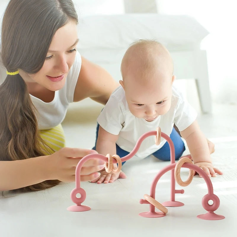 Woman and baby playing with pink baby toys on a white surface