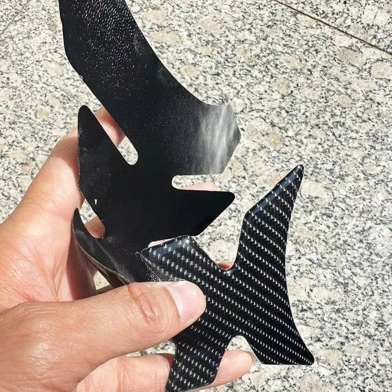 Carbon fiber winglet held by a hand on a textured surface