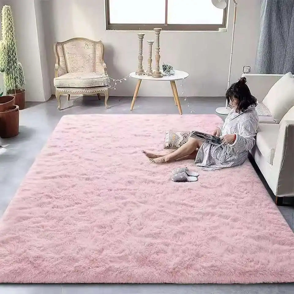 Woman sitting on a pink rug in a living room with a white sofa and decorative items.