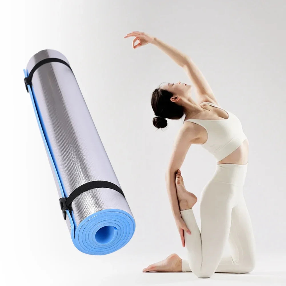 Yoga mat with carrying strap next to a person in a yoga pose on a white background