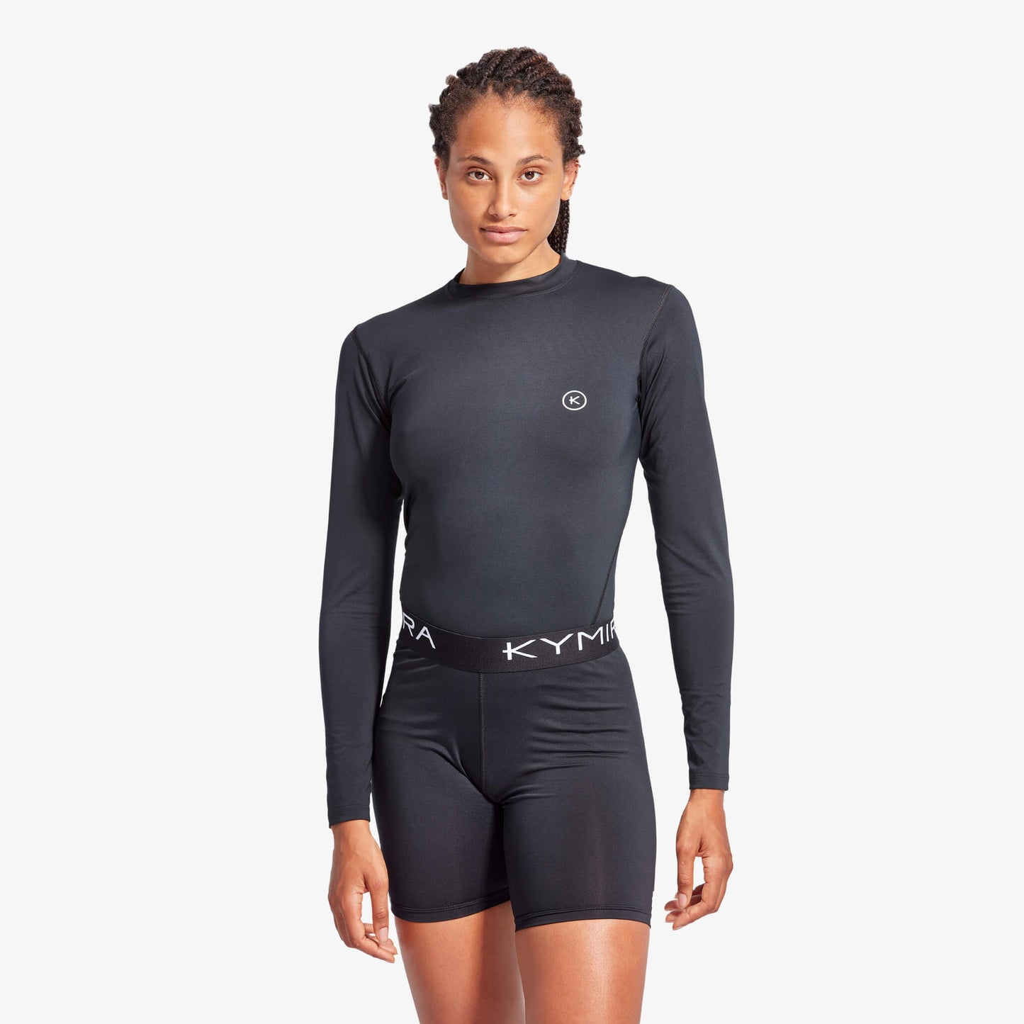 Person wearing a black long-sleeve athletic outfit with 'Kyma' branding on a white background