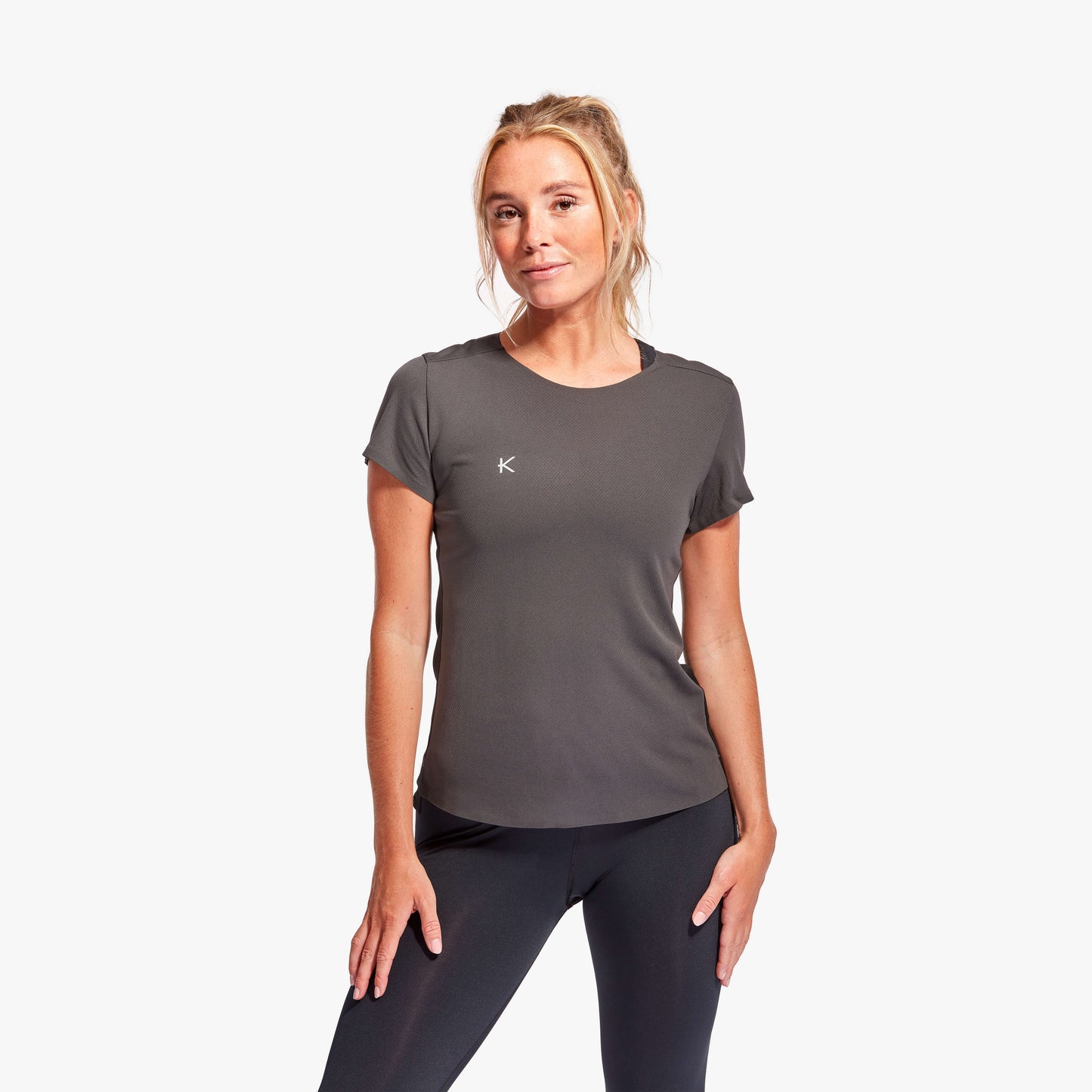 Woman wearing a gray athletic shirt with a logo on a white background