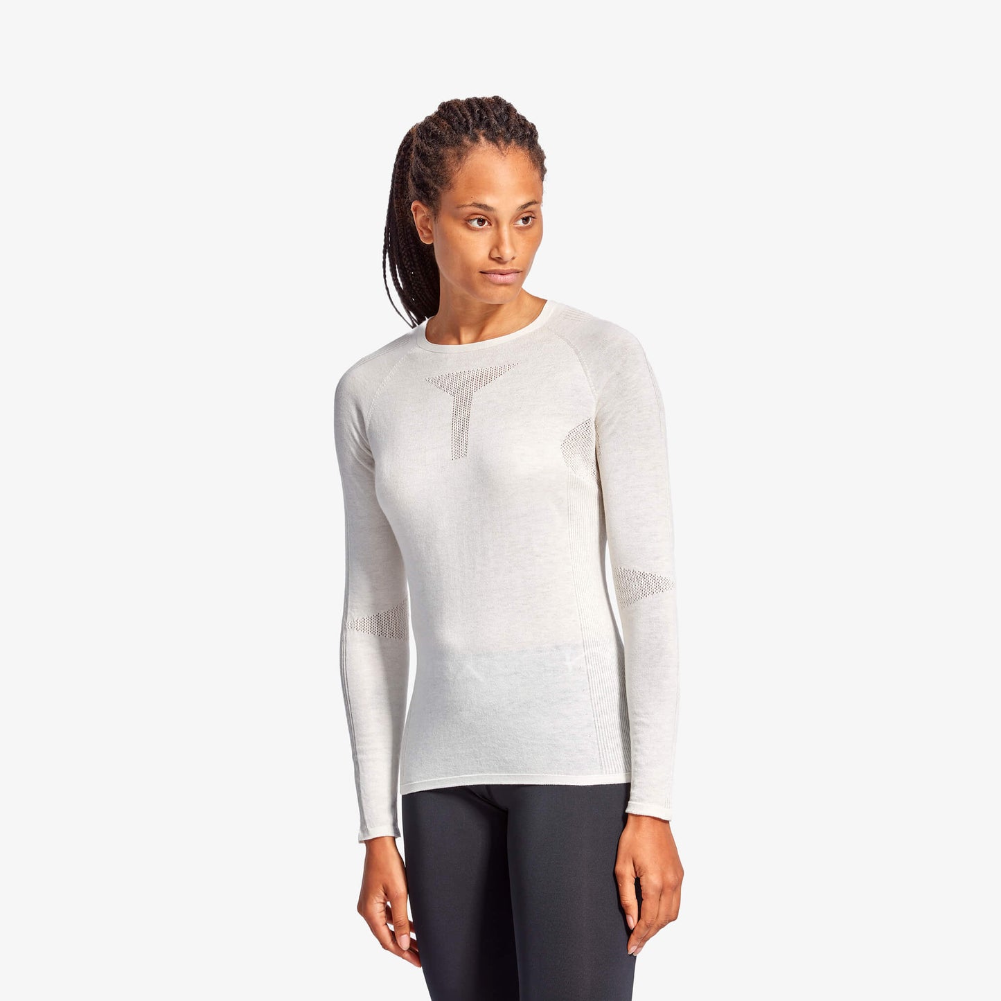 Woman wearing a white long-sleeve top and dark pants on a white background