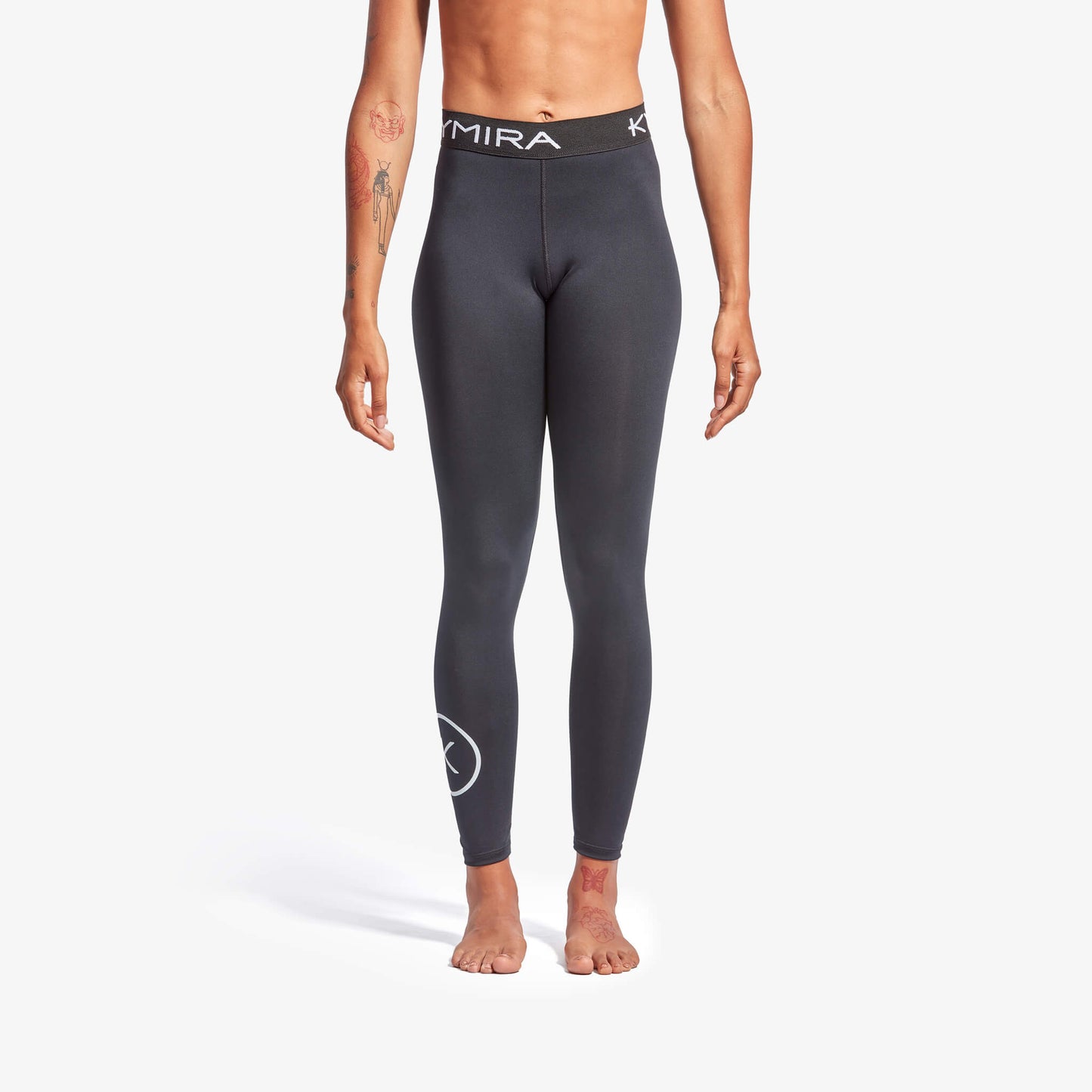 Person wearing dark gray leggings with a brand logo on a white background