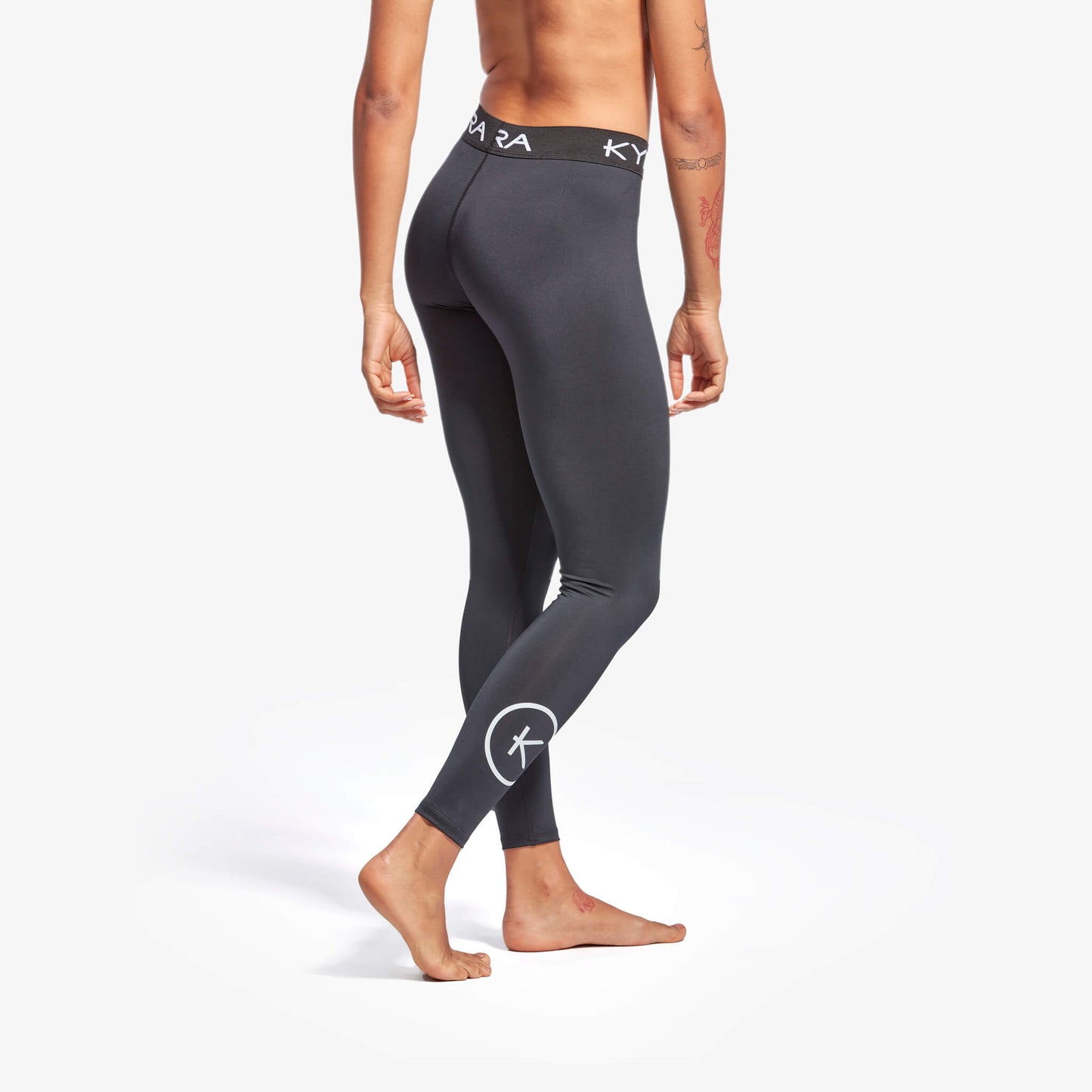 Person wearing black leggings with a logo on a white background