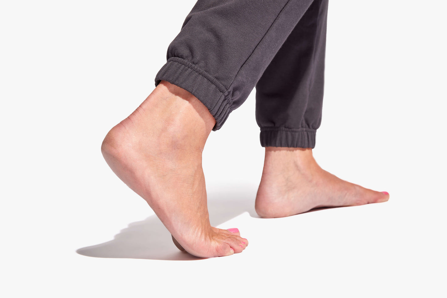 Close-up of a person's feet wearing gray sweatpants on a white background