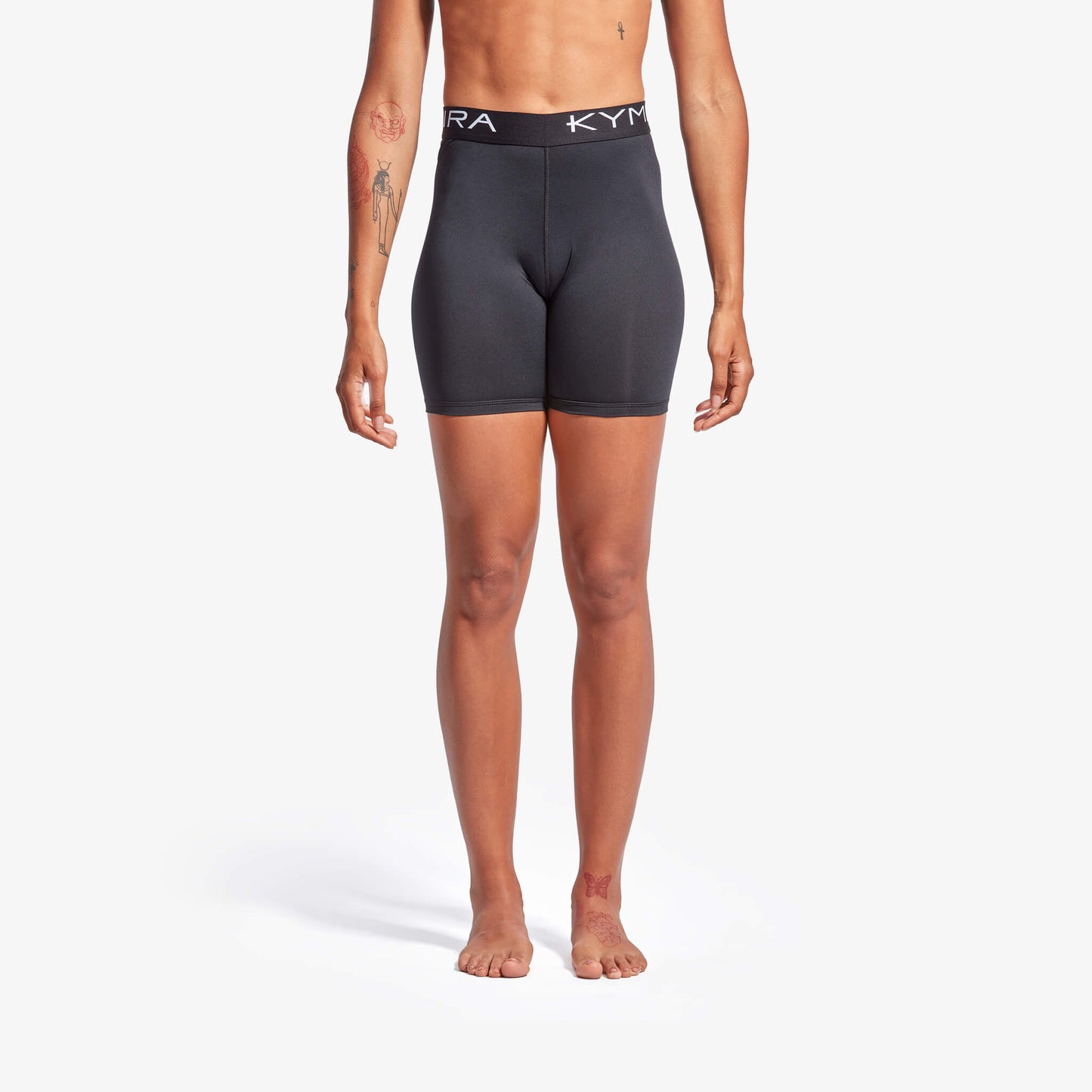 Person wearing black athletic shorts with a visible brand logo on a white background