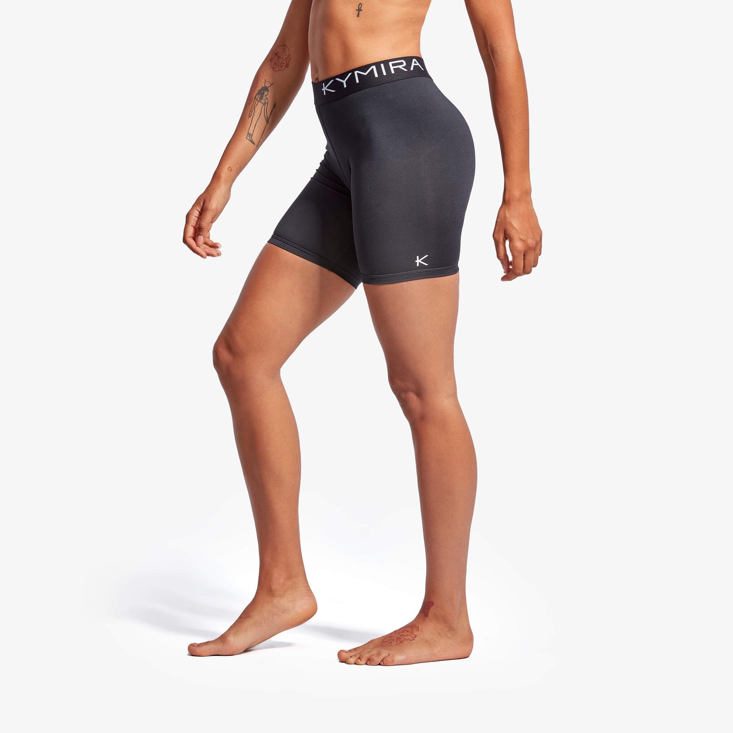 Person wearing black athletic shorts with Kymira branding on a white background