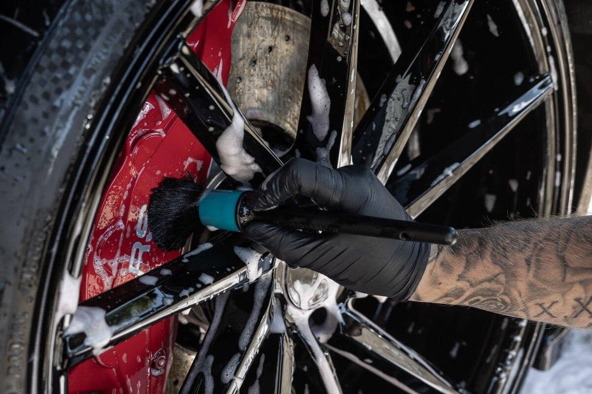 Person cleaning a motorcycle wheel with a brush