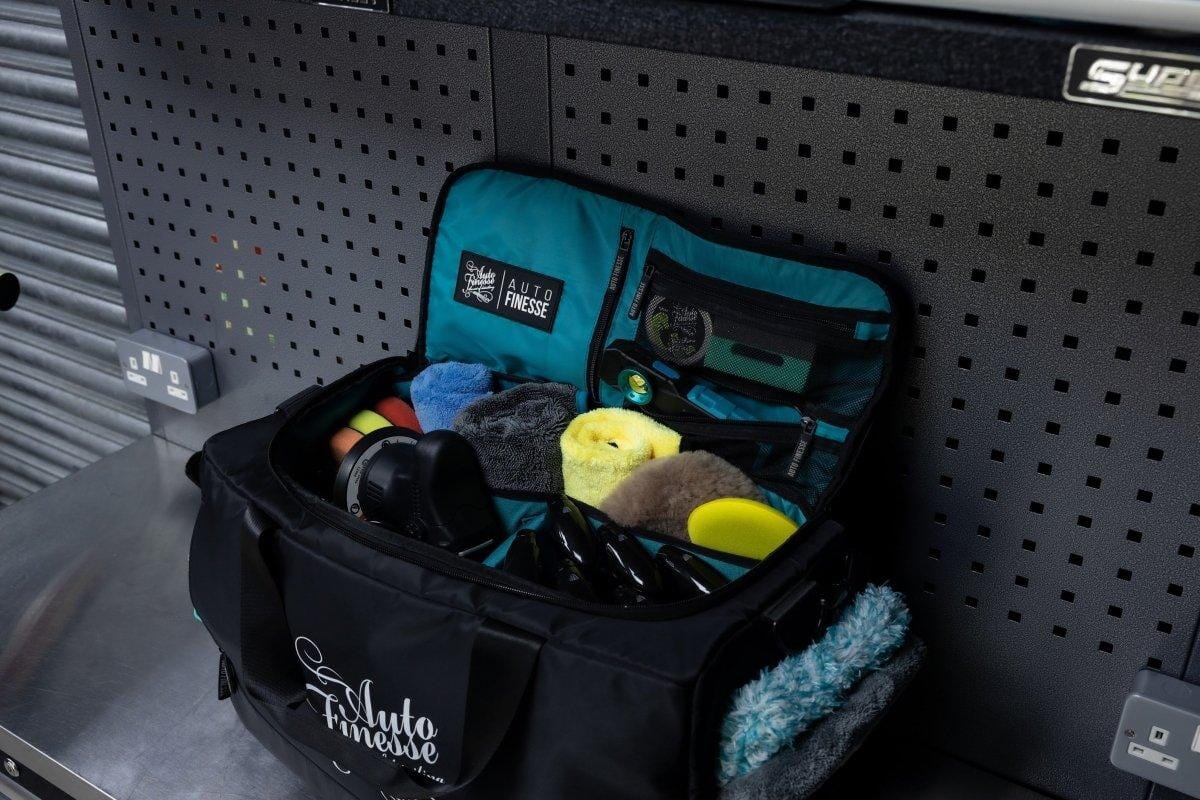 Black and teal tackle bag with fishing gear on a pegboard wall
