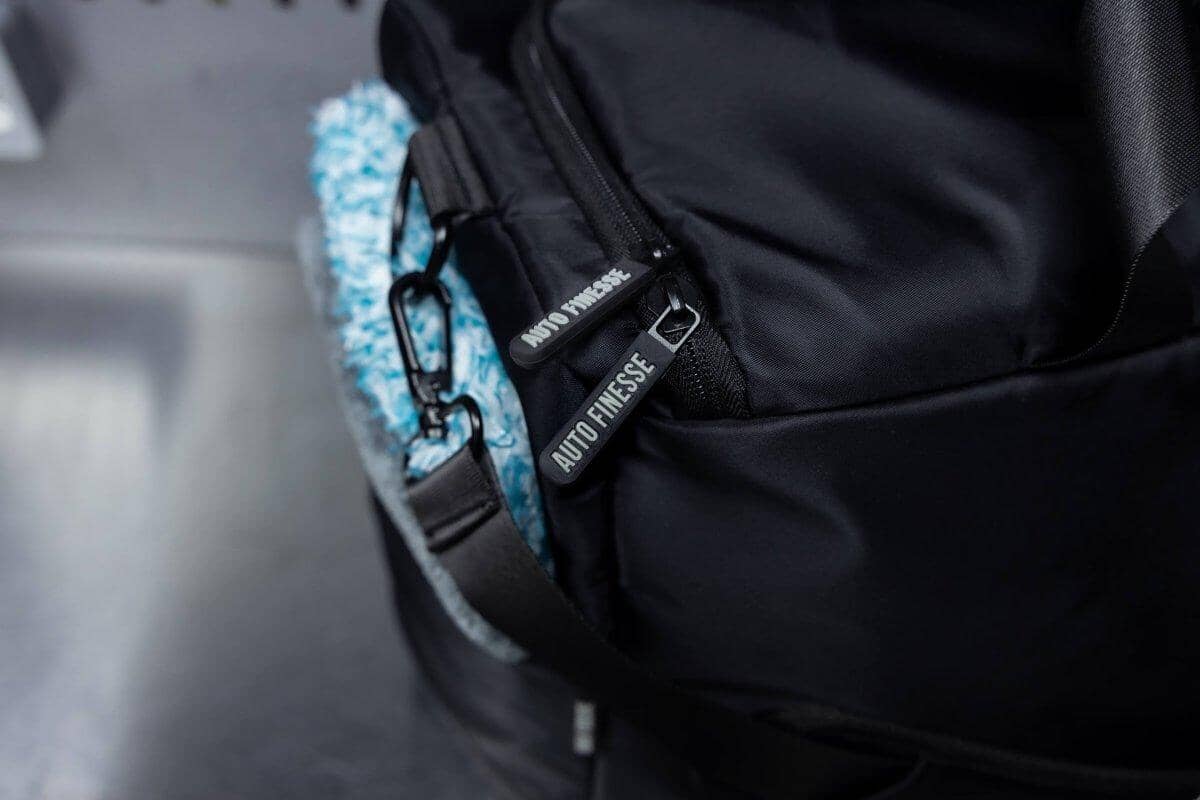Close-up of a black bag with a visible brand logo on a blurred background