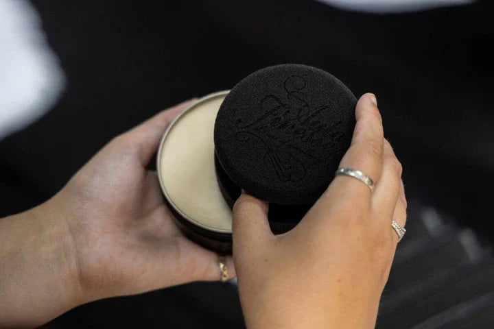 Person holding a black makeup compact with an Auto Finesse logo.