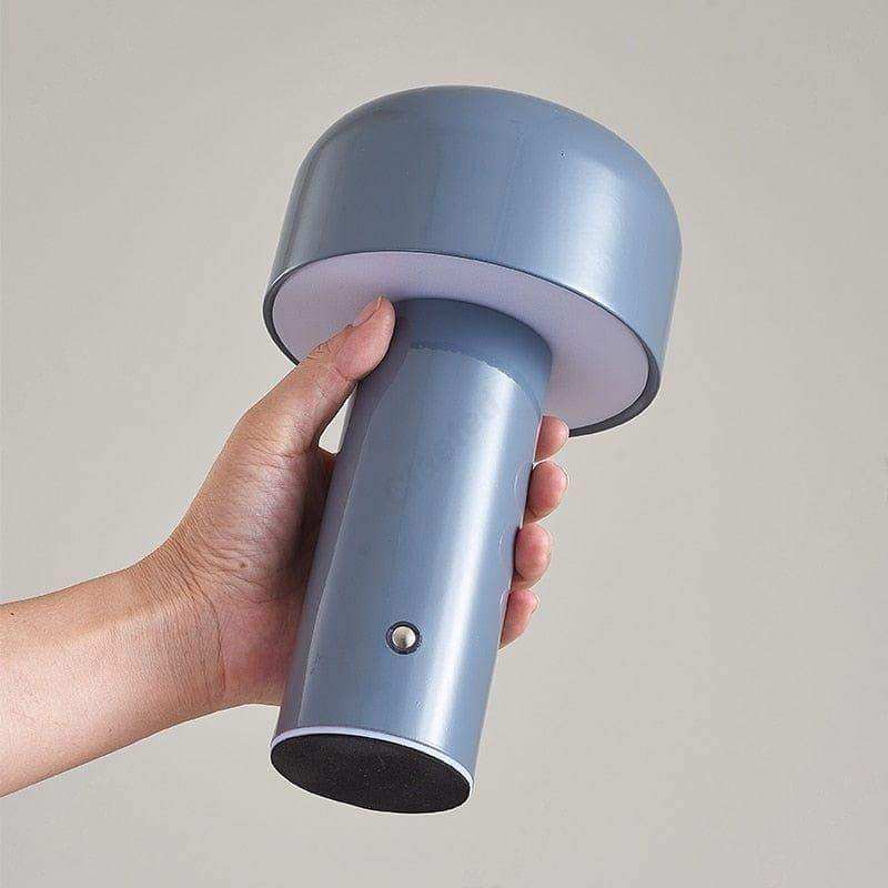 Hand holding a blue handheld lamp against a plain background