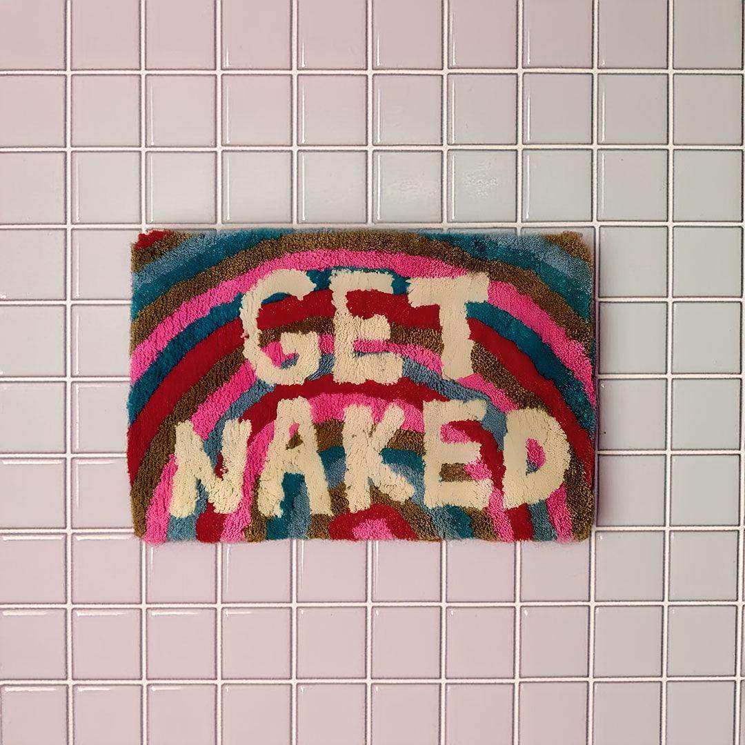 Colorful doormat with 'GET NAKED' text on a tiled floor