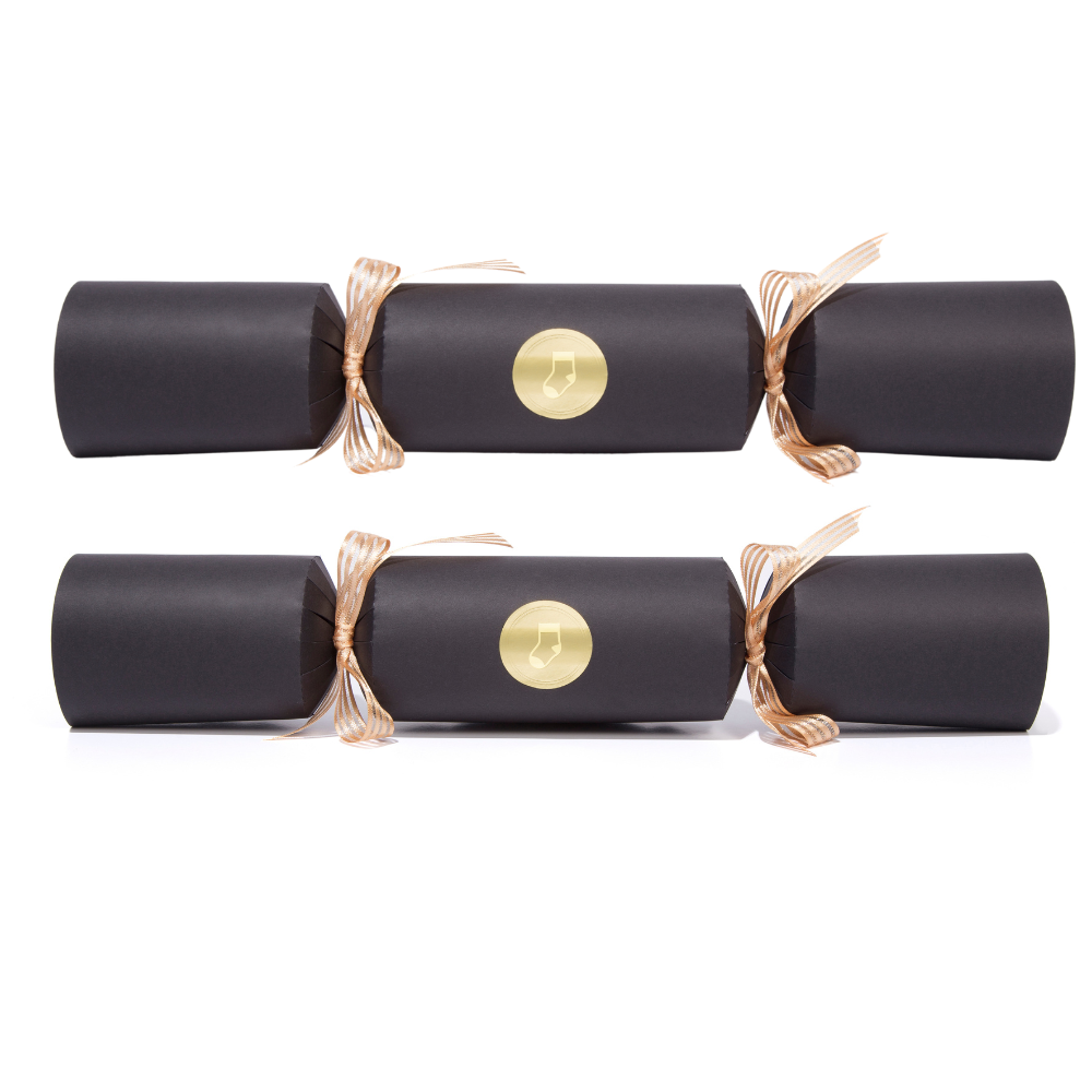 Two black Christmas crackers with gold ribbons and a gold button on a white background