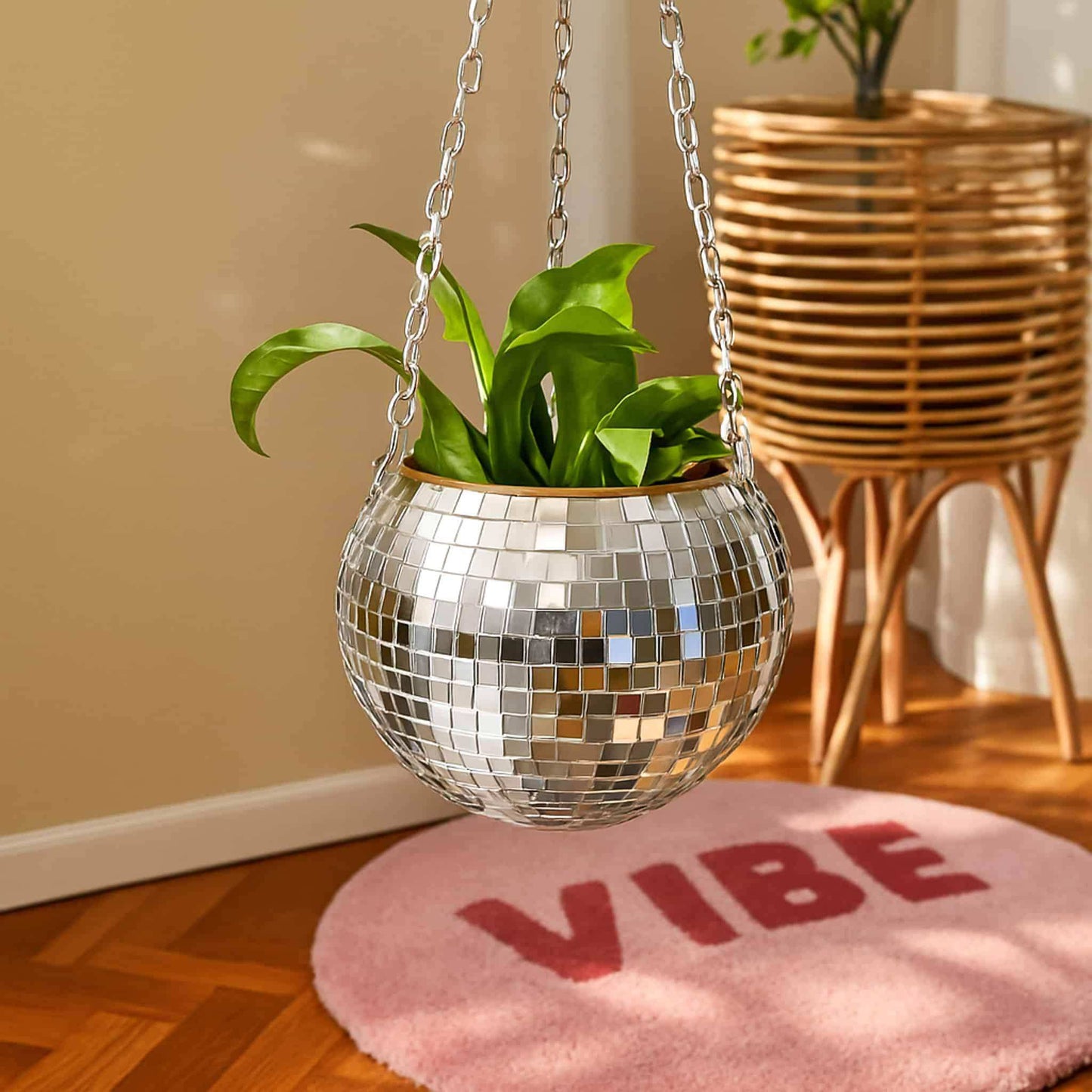 Silver disco ball planter with green plant on a pink rug with 'VIBE' text.