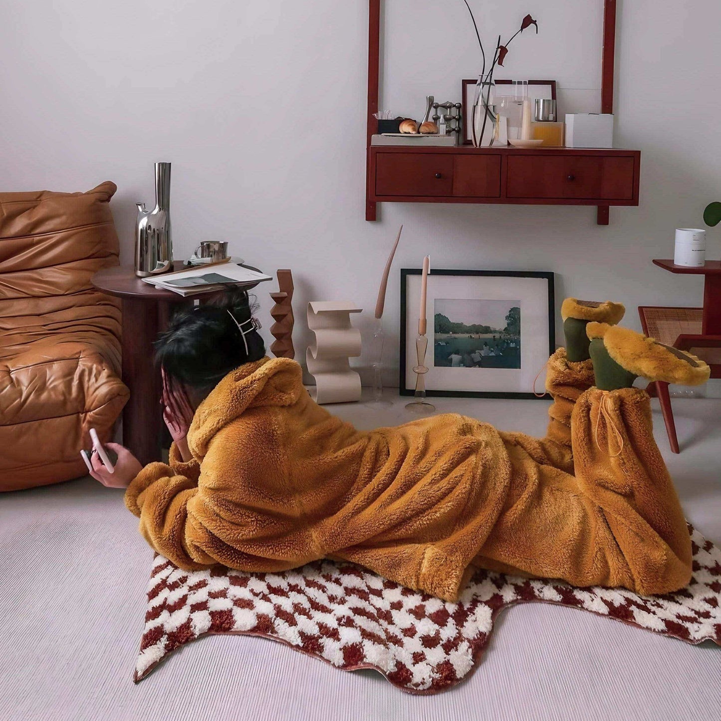 Person in a mustard yellow robe lying on a patterned rug in a living room.