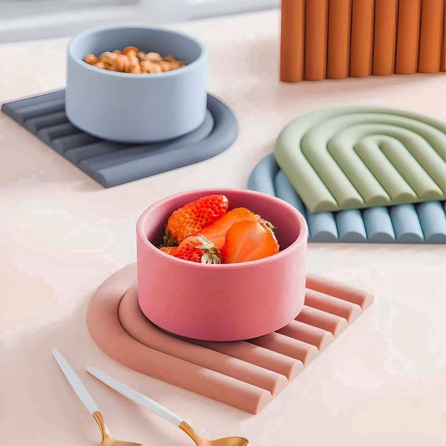Colorful bowls with food on a table with various coasters and a candle.