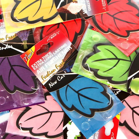Colorful air freshener packages shaped like leaves on a black background
