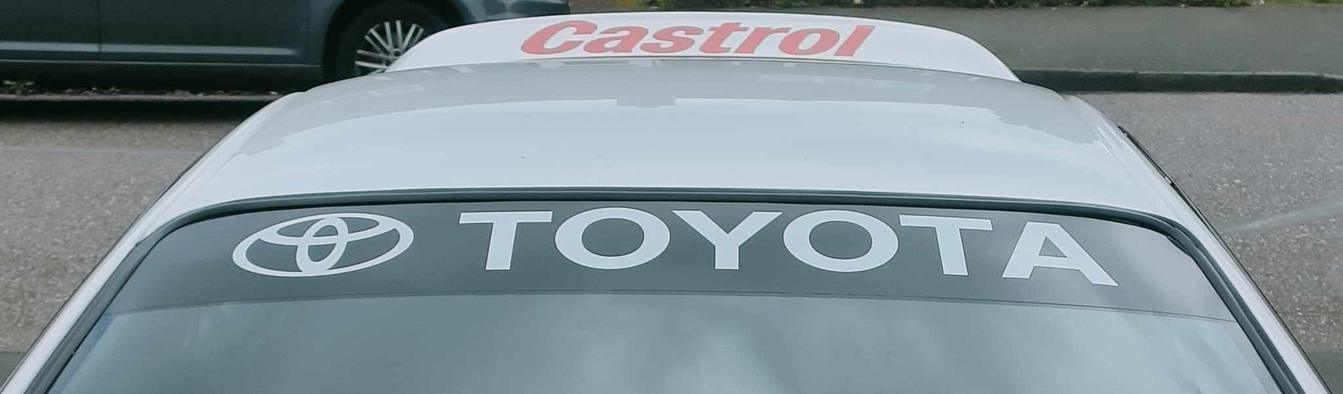 Car window with Toyota and Castrol logos on a road background