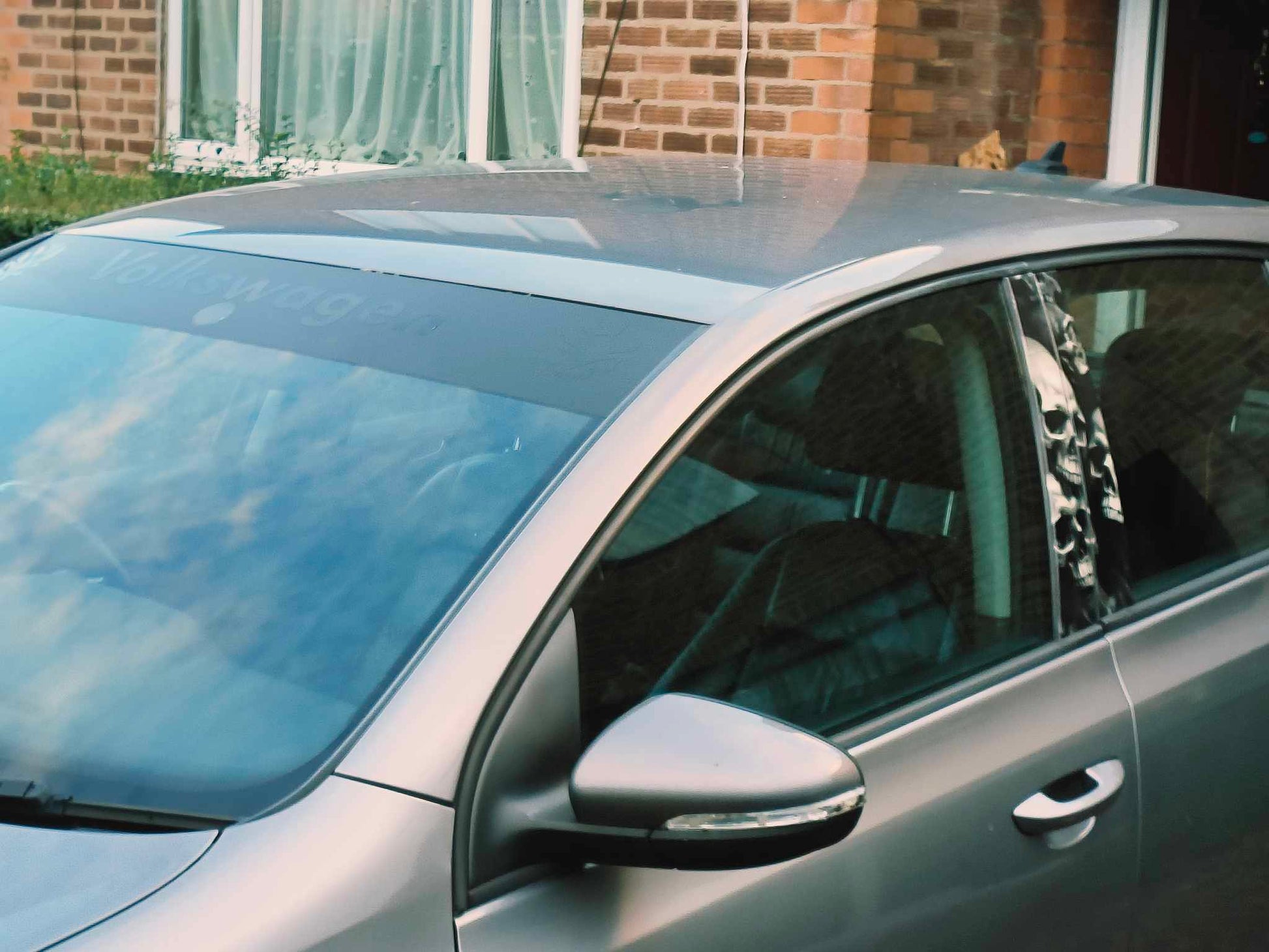 Silver car parked in front of a brick building with a person inside