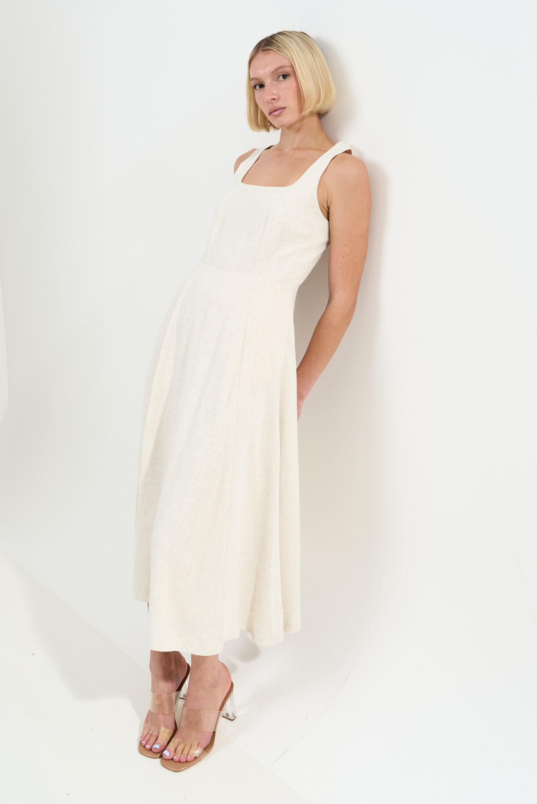 Woman wearing a white sleeveless dress against a white background