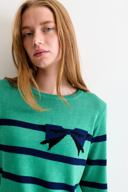 Person wearing a green sweater with blue stripes and a black bow design.