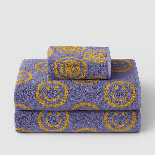 Set of purple towels with yellow smiley face patterns on a light gray background