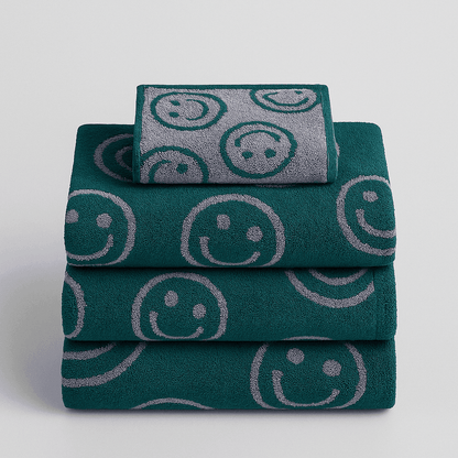 Stack of green towels with smiley face patterns on a light gray background