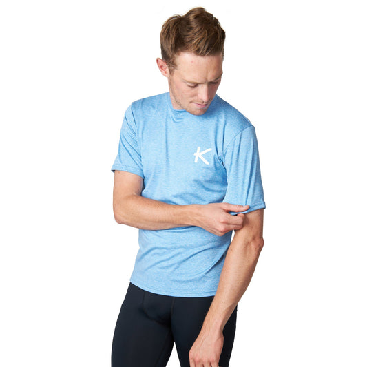 Man wearing a light blue t-shirt with a logo on a white background