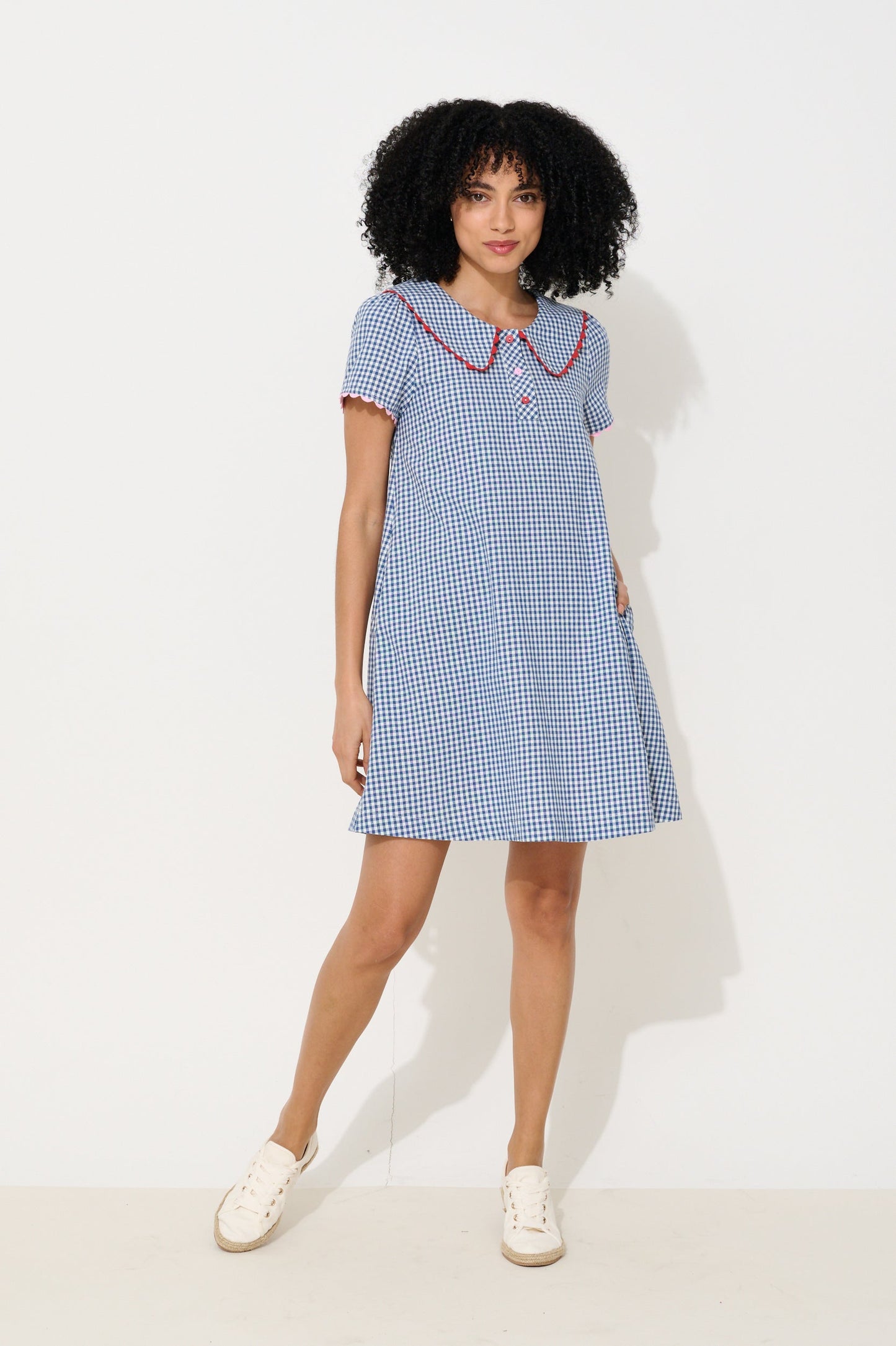 Woman wearing a blue checkered dress with a white background