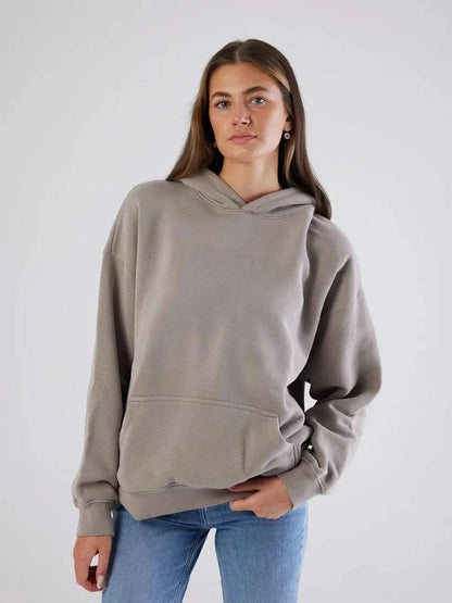 Woman wearing a gray hoodie and blue jeans against a white background