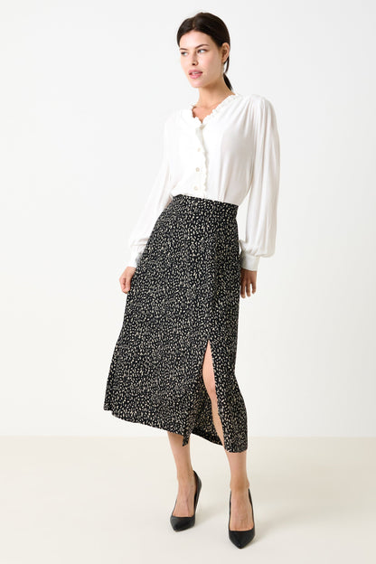 Woman wearing a white blouse and black patterned skirt on a white background