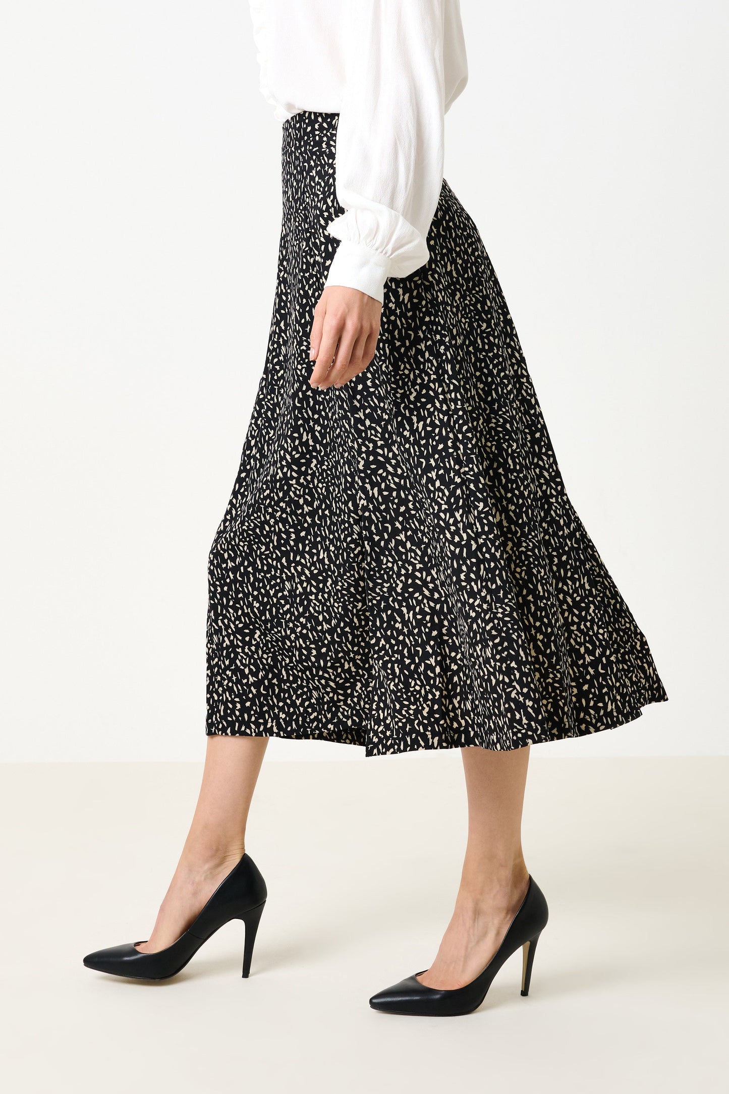 Person wearing a black and white patterned skirt with a plain background