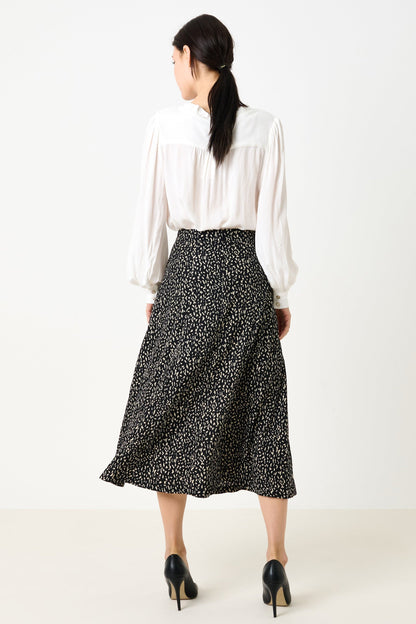 Woman wearing a white blouse and black patterned skirt on a white background