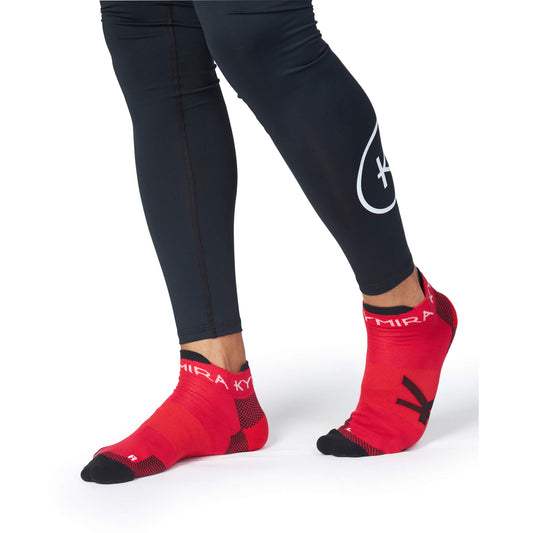 Red socks with black accents worn with black leggings on a white background
