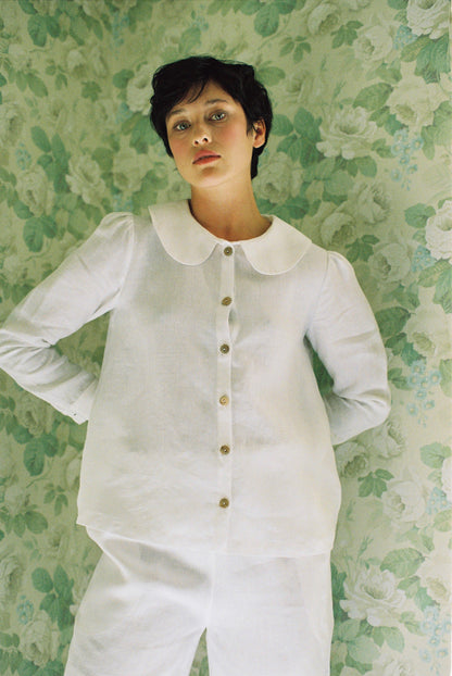 Person wearing a white outfit with a floral patterned wall background
