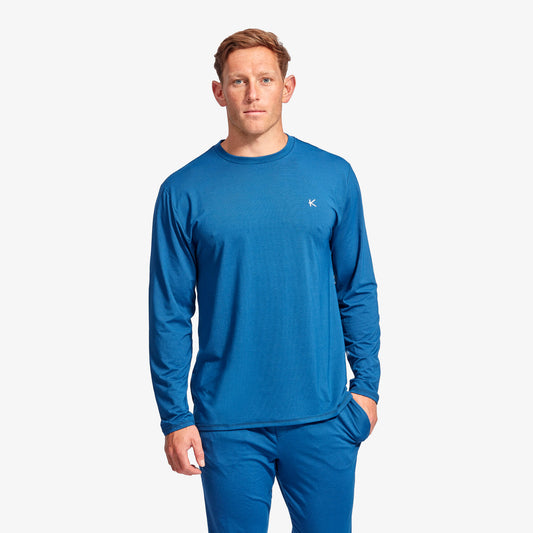 Man wearing a blue long-sleeve shirt and pants on a white background