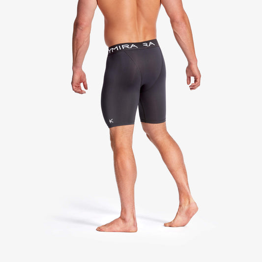 Person wearing black swim shorts with 'Dyamira' branding on a white background