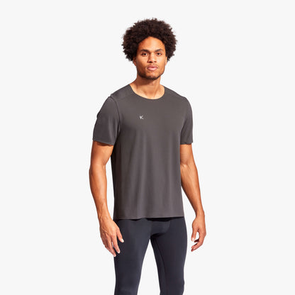 Man wearing a gray athletic shirt and black leggings on a white background