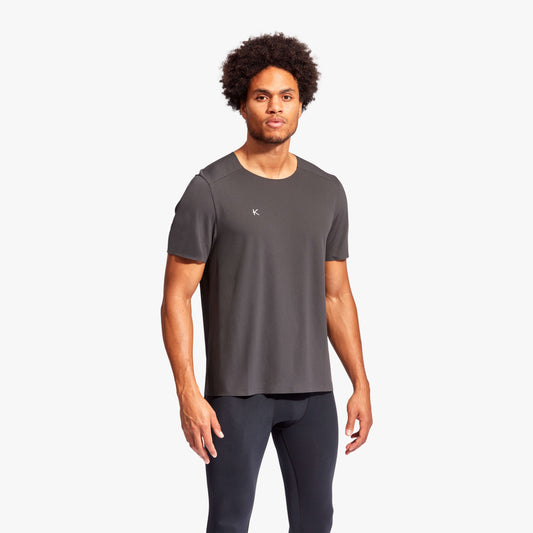 Man wearing a gray athletic shirt and black leggings on a white background