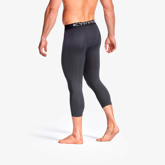 Person wearing black compression leggings with 'Kymia' branding on a white background