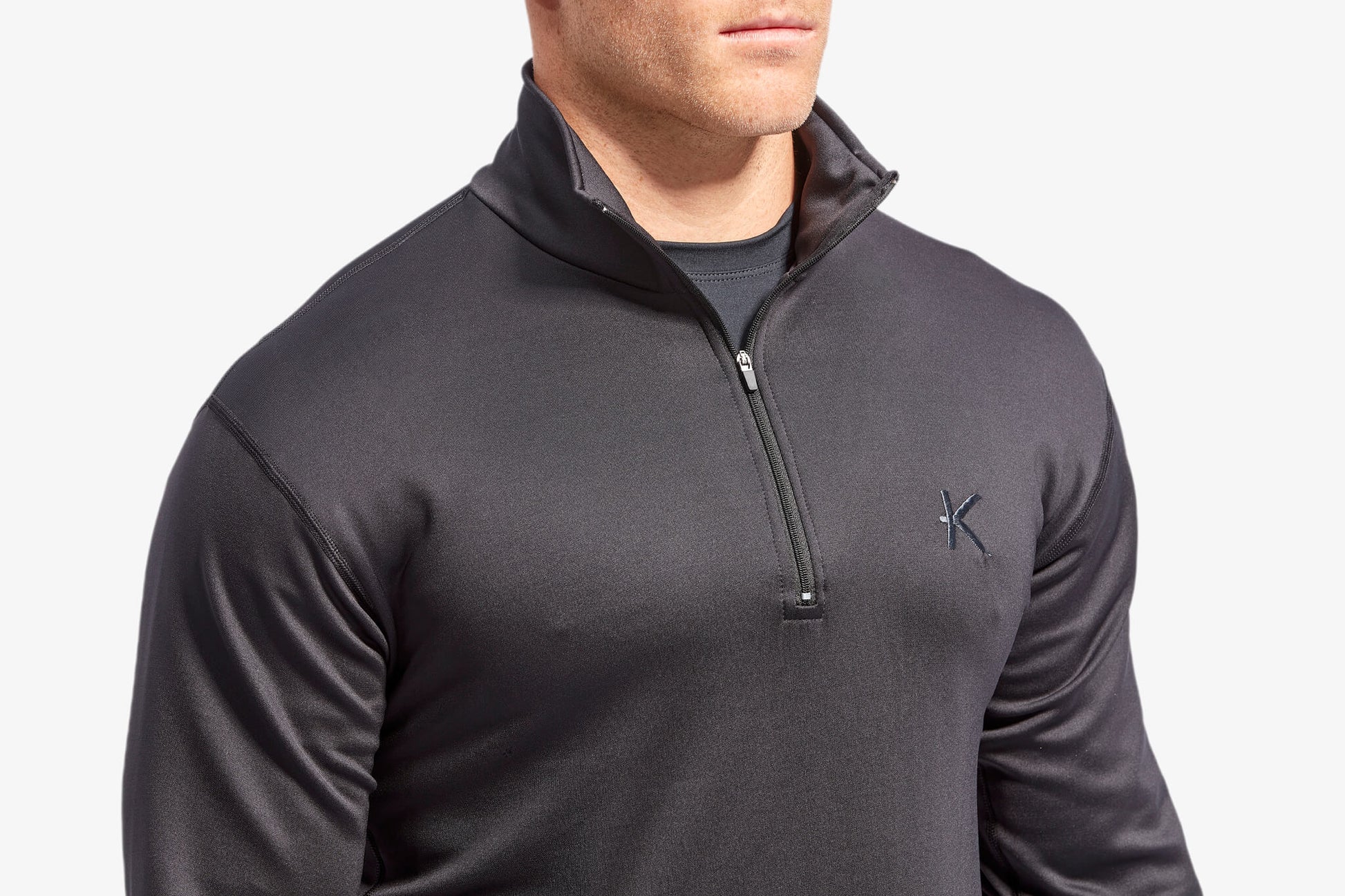 Man wearing a dark gray quarter-zip pullover with a brand logo on a light gray background