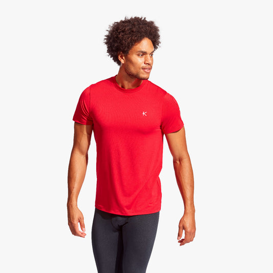 Man wearing a red athletic shirt with a logo on a white background