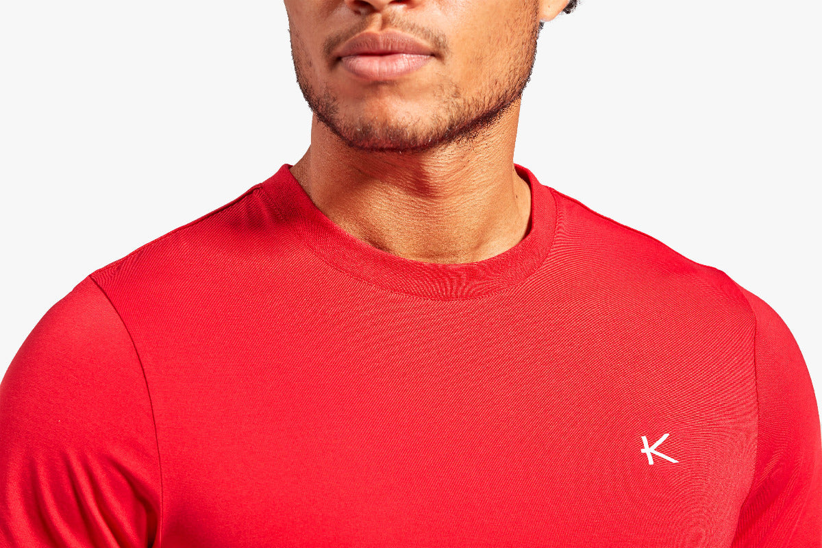 Red athletic shirt with a logo on a white background